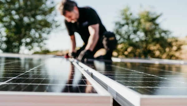technician man assembling solar panels on house roof for self consumption energy